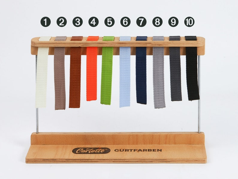 May include: A wooden display stand with ten colored fabric samples. The colors include cream, brown, orange, green, light blue, navy, gray, dark gray, and black. The stand has a wooden base and metal supports, with the brand name "Carlotte" visible.