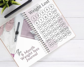 May include: A spiral bound journal with a pink and white design. The cover says "The 6 Month Weight Loss Journal". The inside of the journal has a chart titled "Weight Lost" with numbers 1 through 35 in circles.