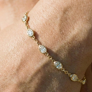 Puede incluir: Un delicado brazalete de oro con diamantes de talla ovalada. La cadena del brazalete está hecha de pequeños eslabones interconectados, y los diamantes están engastados en biseles individuales. Una pieza de joyería clásica.