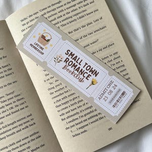 May include: A bookmark with a vintage ticket design featuring a floral illustration and the text "Small Town Romance Bookclub". The bookmark also includes a ticket with the text "Admit One 23 08 24" and a barcode.