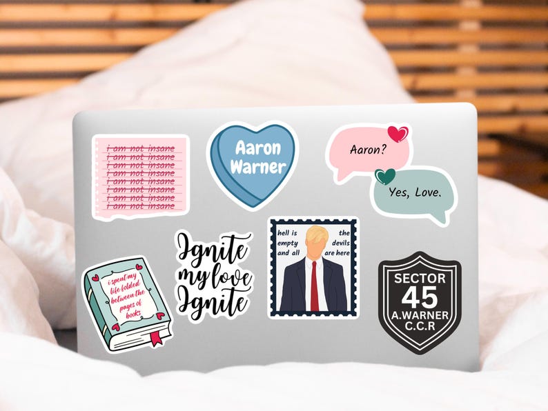 May include: A laptop computer with several stickers on it. The stickers are various colors and feature text and images. The text on the stickers includes "I am not insane", "Aaron Warner", "Ignite my love Ignite", "hell is empty and all", "the devils are here", "Aaron?", "Yes, Love", "SECTOR 45 A.WARNER C.C.R."