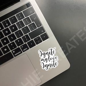 May include: A white laptop with a black keyboard and a sticker that says "Ignite my love Ignite" on the trackpad.