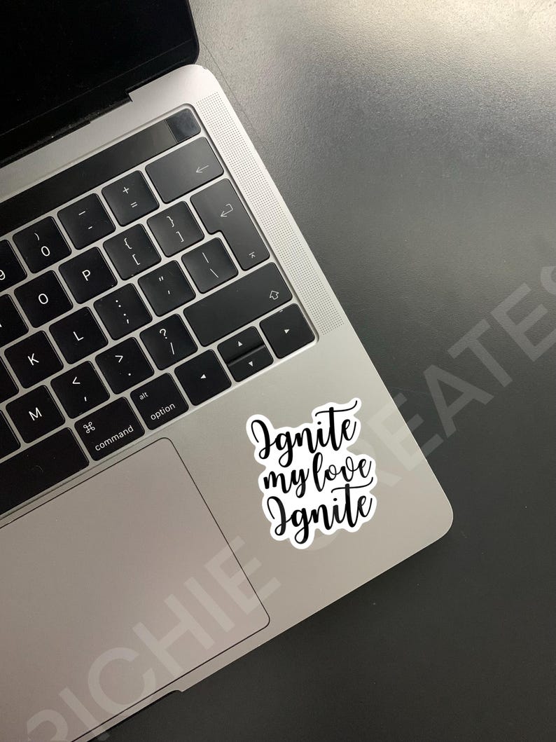 May include: A white laptop with a black keyboard and a sticker that says "Ignite my love Ignite" on the trackpad.