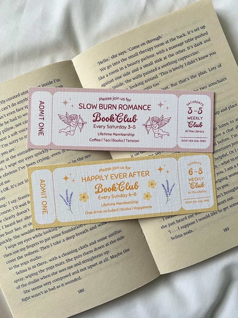 May include: Two pink and yellow bookmarks with a whimsical design. The bookmarks feature illustrations of cherubs with arrows and text that reads "Slow Burn Romance Book Club" and "Happily Ever After Book Club".