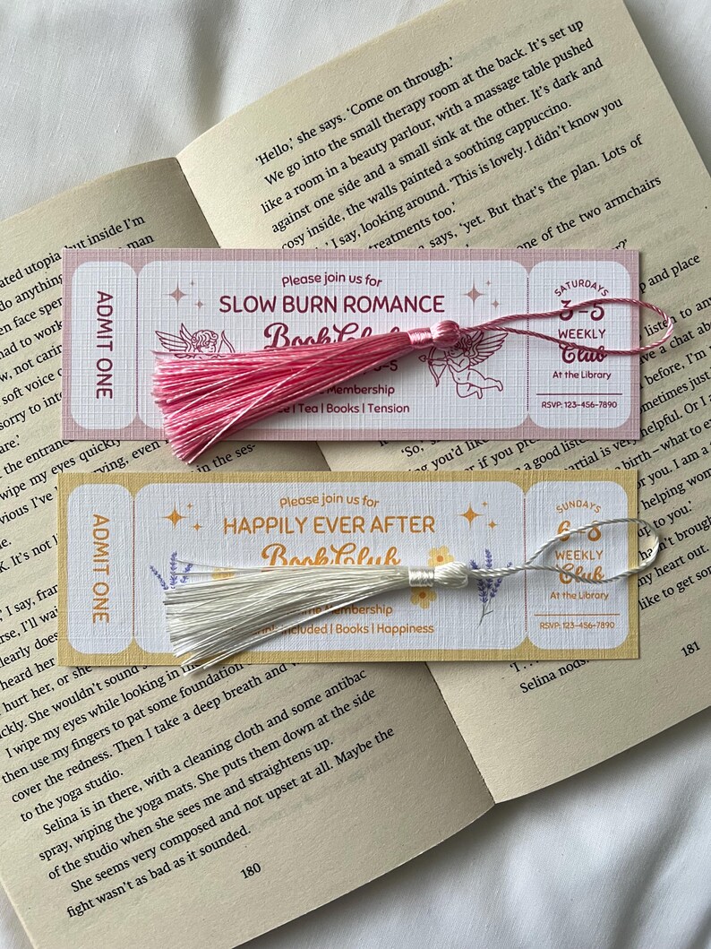 May include: Two pink and white bookmark tickets with tassels. The pink bookmark has the text "Please join us for Slow Burn Romance Book Club" and the white bookmark has the text "Please join us for Happily Ever After Book Club".