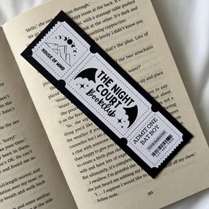 May include: Black and white bookmark with a bat design and the text "The Night Court Bookclub". The bookmark also features a smaller design with the text "House of Wind".