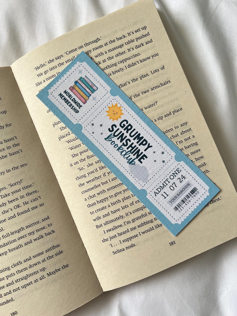 May include: A blue and white bookmark with a sun and the text "Grumpy Sunshine Bookclub" on it. The bookmark also has a ticket-style design with the text "Admit One 11 07 24" and a barcode.