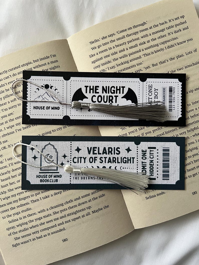 May include: Two black and white bookmark designs with silver tassels. The first bookmark features a bat with the text "The Night Court". The second bookmark features a moon and stars with the text "Velaris City of Starlight".