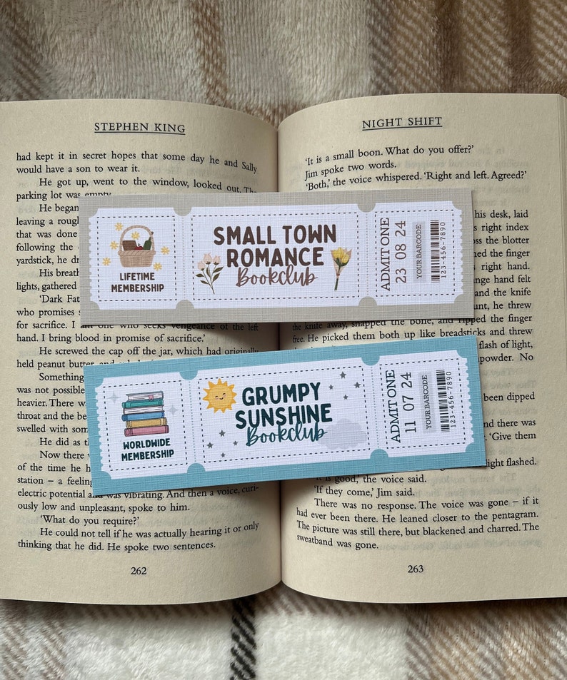 May include: Two colorful bookmarks with a book club theme. The top bookmark is light blue with a white and brown illustration of a small town and the text "Small Town Romance Bookclub". The bottom bookmark is light blue with a yellow sun and the text "Grumpy Sunshine Bookclub".