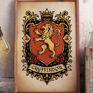 May include: A framed poster of the Gryffindor crest. The crest depicts a golden lion on a red shield, framed by elaborate gold and black embellishments. The word "Gryffindor" is displayed on a banner beneath the crest. The poster is set in a wooden frame.