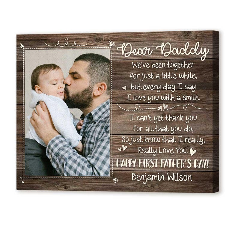 Puede incluir: Impresi&oacute;n en lienzo enmarcada en madera con una fotograf&iacute;a de un padre besando a un beb&eacute;. El texto dice "Querido Pap&aacute;" y un mensaje del D&iacute;a del Padre. El fondo tiene una textura de vetas de madera.