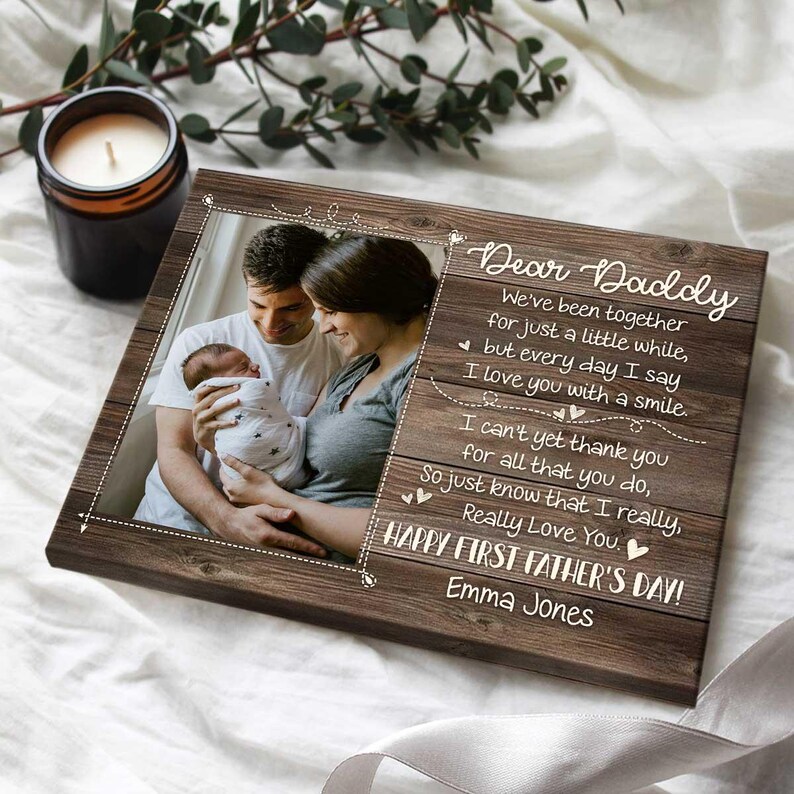 Puede incluir: Una impresi&oacute;n fotogr&aacute;fica enmarcada en madera con un retrato familiar y el texto "Querido Pap&aacute;". La foto muestra a una pareja sosteniendo a un reci&eacute;n nacido. El texto incluye un mensaje del D&iacute;a del Padre y el nombre "Emma Jones".