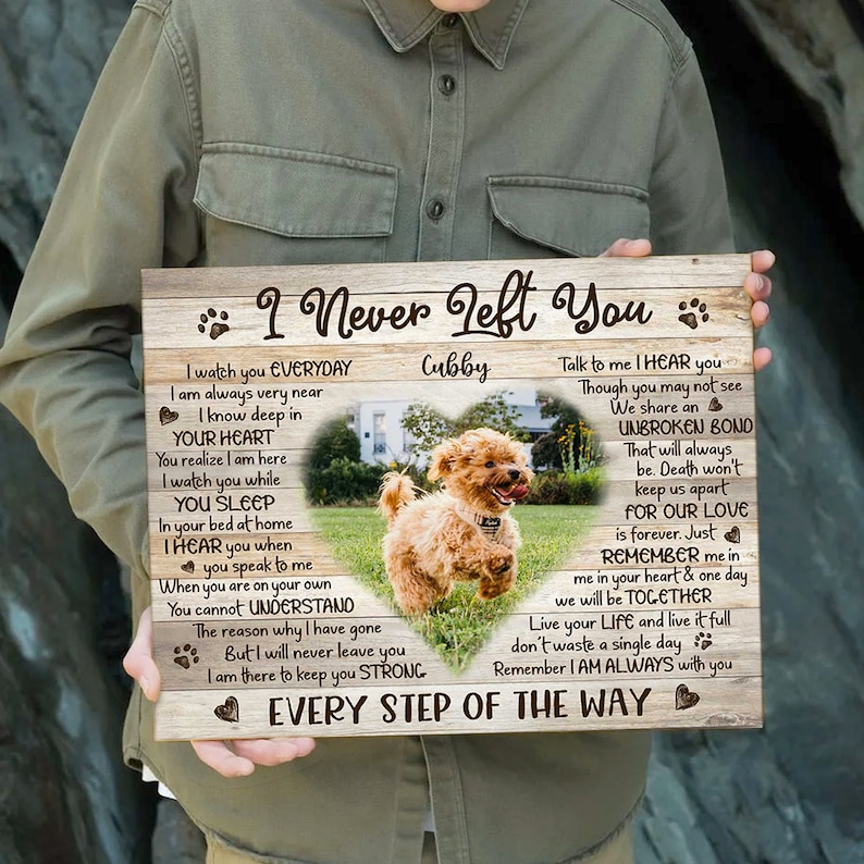 May include: A wooden sign with a heart-shaped cutout featuring a photo of a small, light brown dog. The sign has a woodgrain background and the text "I Never Left You" with the name "Cubby" and a message about an unbreakable bond and love that lasts forever.