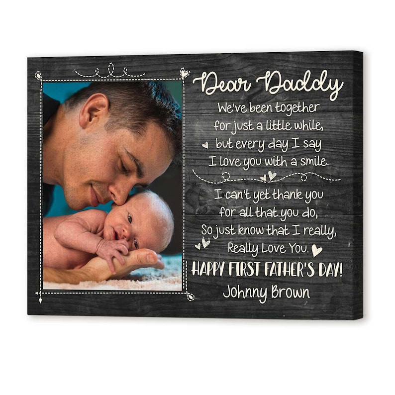 Puede incluir: Impresi&oacute;n en lienzo enmarcada con una foto de un padre y un beb&eacute;, con el texto "Dear Daddy" y un mensaje del D&iacute;a del Padre. El fondo es un patr&oacute;n de vetas de madera oscura.