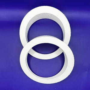 May include: Two white foam wreath forms, one slightly larger than the other, are arranged on a blue background. The circular wreaths have a textured surface, suitable for crafting or decoration. The image is well-lit, highlighting the clean, simple design.
