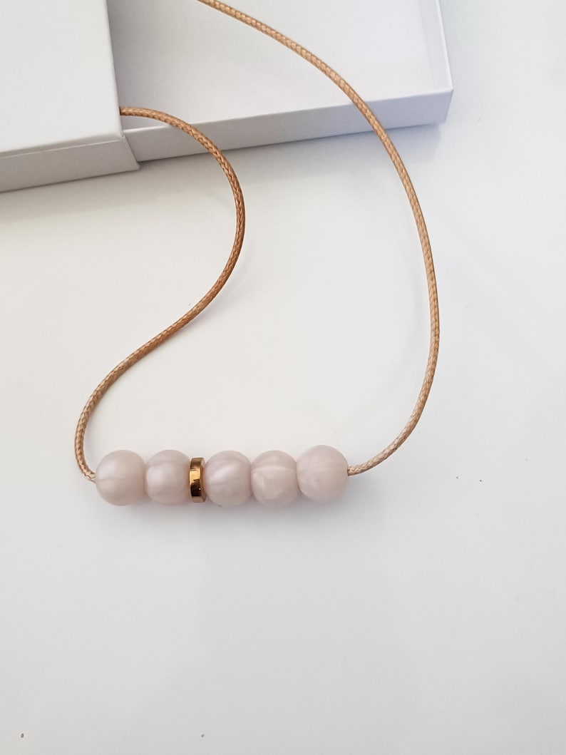 Pink pearl silicone necklace of five small beads seperated with a rose gold spacer bead, necklace placed in giftbox.