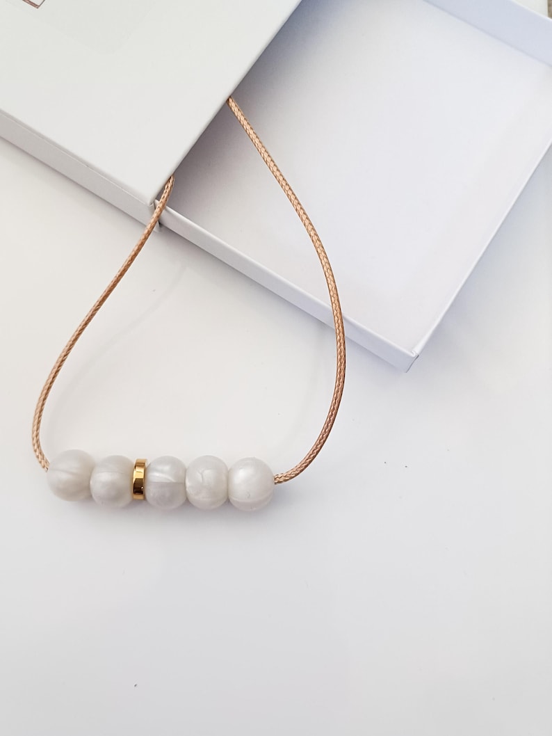 white pearl silicone necklace of five small beads separated with a rose gold spacer bead, necklace placed in giftbox.