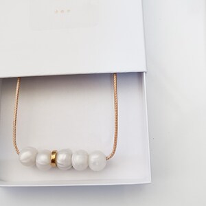 Pink pearl silicone necklace of five small beads separated with a rose gold spacer bead, necklace placed in giftbox.