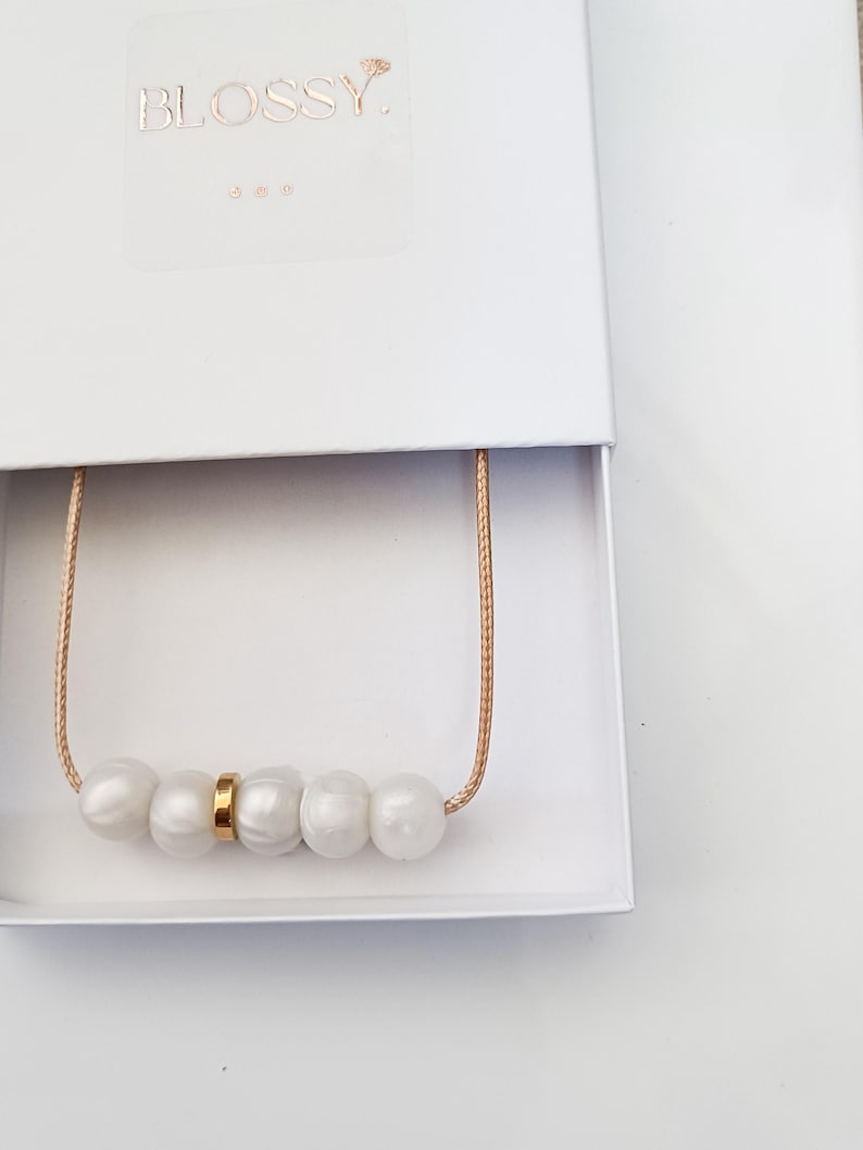 Pink pearl silicone necklace of five small beads separated with a rose gold spacer bead, necklace placed in giftbox.