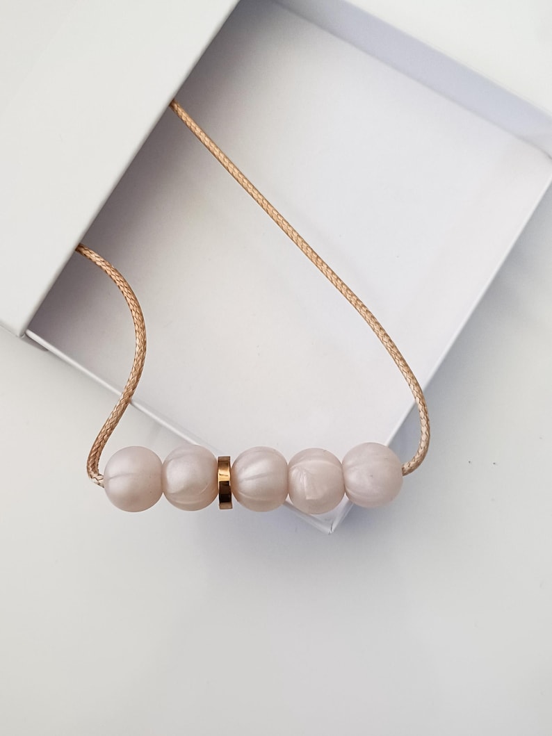 Pink pearl silicone necklace of five small beads separated with a rose gold spacer bead, necklace placed in giftbox.