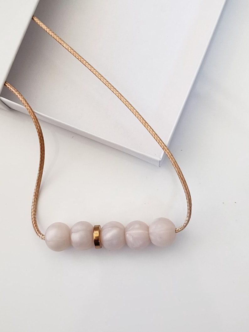 Pink pearl silicone necklace of five small beads separated with a rose gold spacer bead, necklace placed in giftbox.