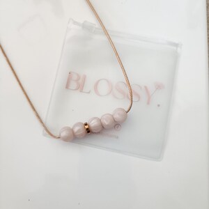 Pink pearl silicone necklace of five small beads separated with a rose gold spacer bead, necklace placed in giftbox.
