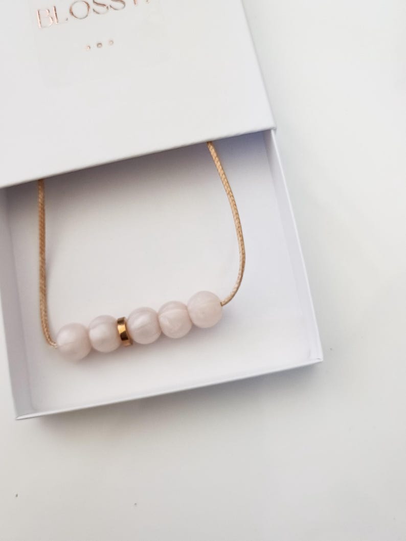 Pink pearl silicone necklace of five small beads separated with a rose gold spacer bead, necklace placed in giftbox.