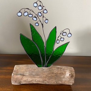 Bouquet de muguet en vitrail incrusté sur une base en bois flotté