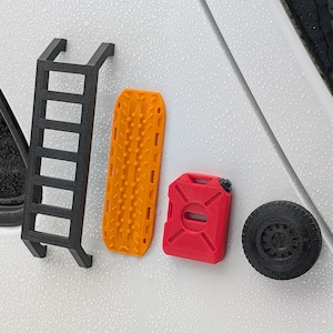 May include: A set of four black, red, and orange 3D printed accessories for an off-road vehicle. The accessories include a ladder, a gas can, a tire, and a traction mat.
