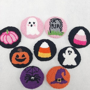 May include: Nine colourful felt ornaments with Halloween themes. The ornaments feature a ghost, a pumpkin, a candy corn, a tombstone, a spider, a witch's hat, a lollipop, a ghost, and a jack-o-lantern.
