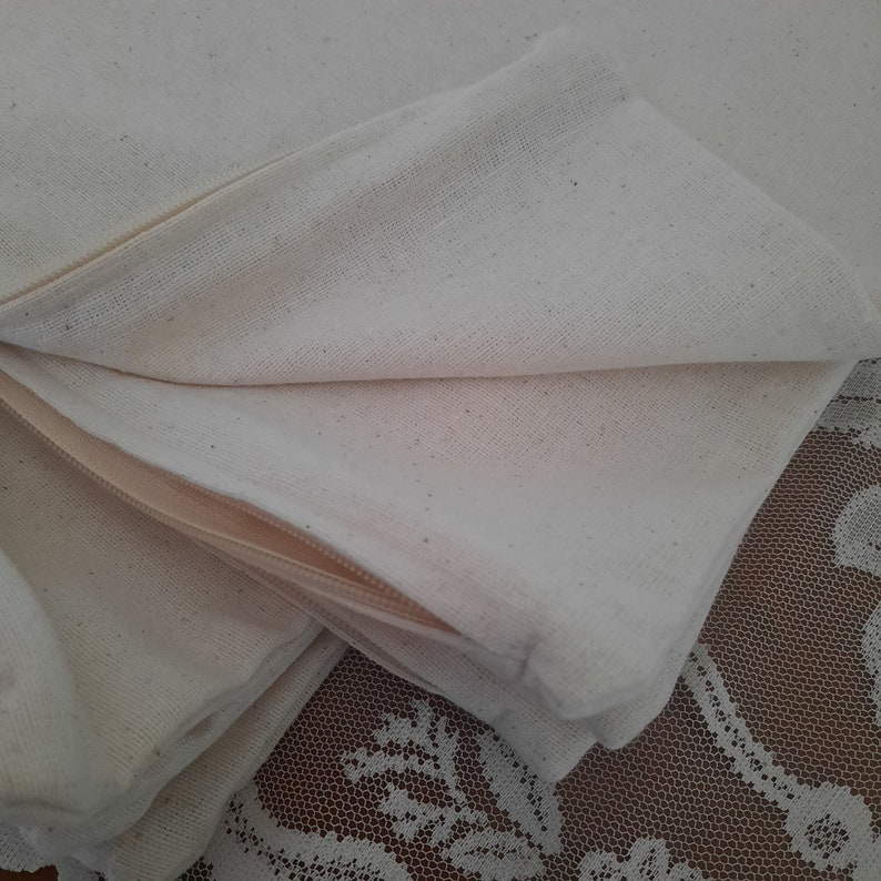 May include: A close-up of a white cotton pillowcase with a zipper. The pillowcase is folded in half and the zipper is visible.