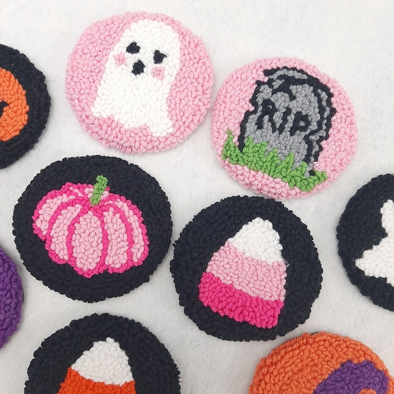 May include: Nine colourful felt circles with various Halloween-themed designs, including a ghost, a pumpkin, a candy corn, a tombstone, and a skull. The circles are all approximately 7.5 cm in diameter and are made with a variety of colours, including pink, black, white, green, and orange.