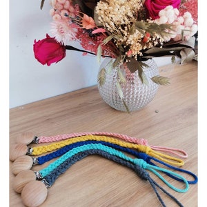 Peut inclure: Cinq attaches-tétines en crochet de couleurs vives avec des perles en bois. Les attaches-tétines sont dans les tons rose, jaune, bleu, turquoise et gris.