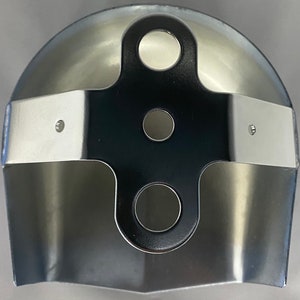 May include: A metallic, semi-circular component featuring a central black cross-shaped bracket. The bracket has three circular holes and is secured to the curved, polished silver-toned metal body with two small rivets on each side.