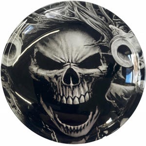 May include: A black and white skull graphic with a detailed design. The skull is surrounded by a black and white background with a swirling pattern.