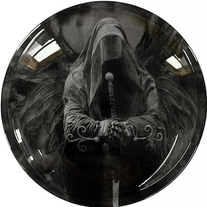 May include: A black and white image of a hooded figure holding a sword. The figure is standing in front of a dark background. The image has a gothic and mysterious feel.