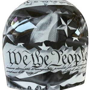 May include: A rounded, dome-shaped object featuring a black and white graphic print of the United States Constitution. The text "We the People" is prominently displayed in a decorative script font, accompanied by star motifs and flag imagery.