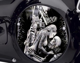 May include: A circular black motorcycle derby cover featuring a graphic of a person with long hair embracing a skeleton. The design includes a motorcycle, flames, and the text Ride Or Die. The cover is secured with five silver bolts.
