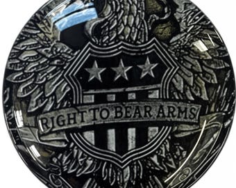 May include: A black and white graphic of an eagle with outstretched wings holding a shield with three stars and the text "RIGHT TO BEAR ARMS".