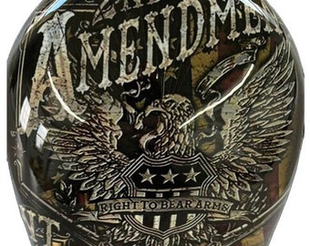 Può includere: Un casco nero e oro con un designo di bandiera americana usurato. Il casco presenta un'aquila con le ali spiegate e il testo "2nd AMENDMENT RIGHT TO BEAR ARMS".