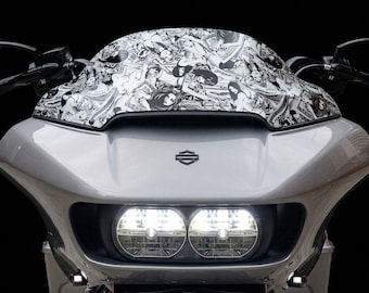 Puede incluir: Un carenado delantero de motocicleta Harley-Davidson plateado con faros LED dobles brillantes y un parabrisas cubierto con un collage gráfico en blanco y negro de varias figuras femeninas ilustradas y patrones intrincados.