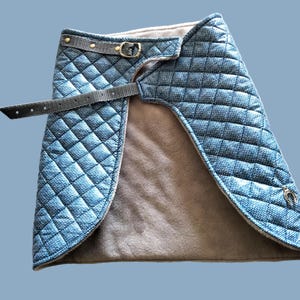 May include: A quilted denim skirt with a brown fleece lining and a black adjustable belt with a gold buckle.