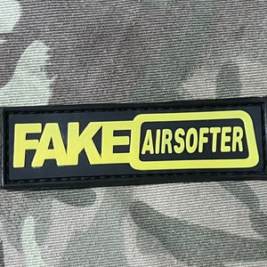 Peut inclure: Patch noir et jaune avec le texte "FAKE AIRSOFTER" en caractères gras et carrés.
