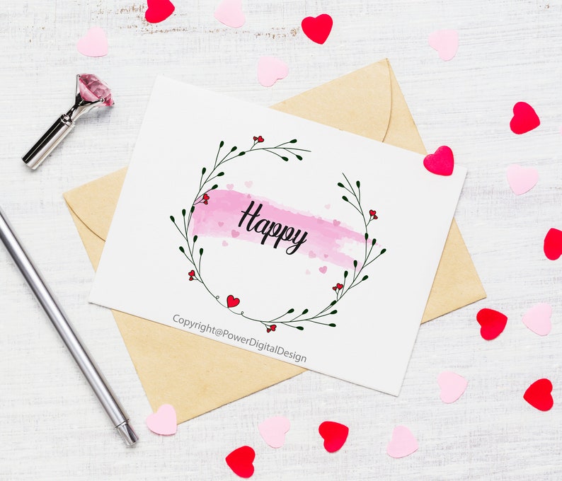 May include: A white card with a pink watercolor background and a black floral wreath with the word "Happy" in the center. The card is surrounded by pink and red hearts on a white wooden surface. The text at the bottom of the card reads "Copyright@PowerDigitalDesign".