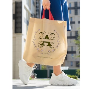 May include: A beige tote bag with a butterfly design featuring the letter "A" in a floral wreath. The text "Copyright@PowerDigitalDesign" is printed on the bag.