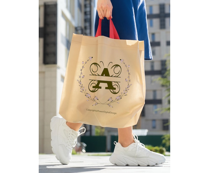 May include: A beige tote bag with a butterfly design featuring the letter "A" in a floral wreath. The text "Copyright@PowerDigitalDesign" is printed on the bag.