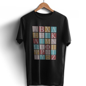 May include: Black t-shirt with a graphic of the Greek alphabet printed in colorful squares. The letters are in a vintage style font.