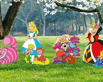 May include: Alice in Wonderland themed cardboard cutouts of Alice, the Mad Hatter, the Cheshire Cat, the Queen of Hearts, and the March Hare. The cutouts are standing on a green grassy lawn.