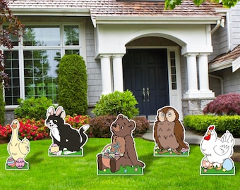 Könnte beinhalten: Oster-Gartendekorationen mit Zeichentricktieren. Das Set umfasst eine Gans, einen schwarz-weißen Hasen, einen braunen Bären, eine Eule und ein Huhn, jeweils mit Ostereiern. Die Dekorationen sind auf einem grünen Rasen vor einem Haus platziert.