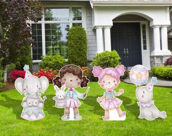 Könnte beinhalten: Vier Pappfiguren mit Zirkus-Motiv. Ein Mädchen mit braunen Haaren und einem rosa Kleid hält einen Zauberstab. Ein Mädchen mit rosa Haaren und einem rosa Kleid hält einen Ballon. Ein grauer Elefant mit einer Partymütze sitzt auf einem rosa-blauen Zirkusring. Ein grauer Seehund mit einer Partymütze hält einen Ballon.